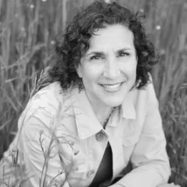 A woman sitting in the grass smiling for a picture.