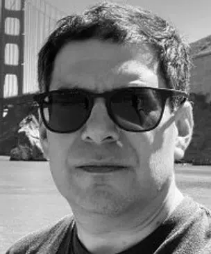 A man wearing sunglasses and standing in front of the golden gate bridge.