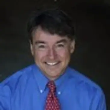 A man in blue shirt and red tie smiling.
