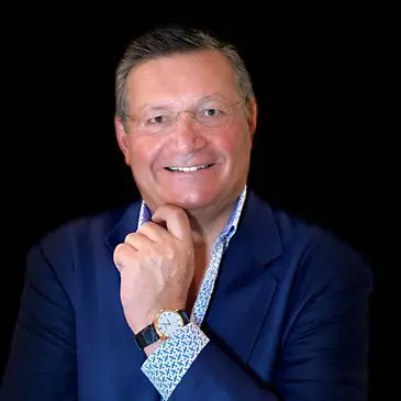 A man in a suit and tie smiling for the camera.