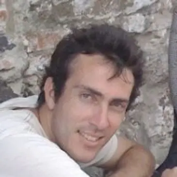 A man smiling for the camera in front of a stone wall.